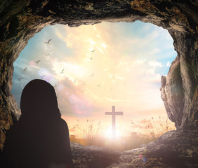 Resurrection of Easter Sunday concept: Jesus Christ is risen from tomb with cross on meadow sunrise background - obrazy, fototapety, plakaty