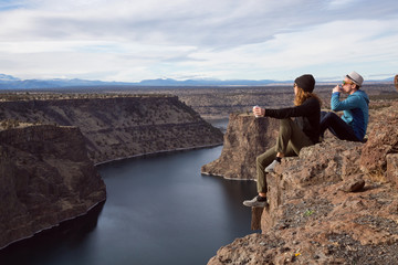 Naklejka premium Friends sitting at the edge of a cliff and enjoying the beautiful landscape. Taken at The Cove Palisades State Park in Oregon, North America.