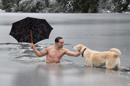 Bizarre picture of a man holiding an umbrella and petting a dog in a frozen lake. Taken in Alice Lake, Squamish, North of Vacouver, BC, Canada.