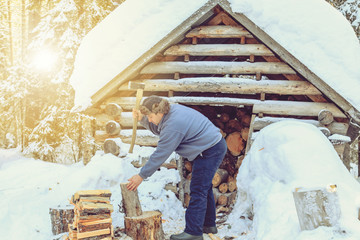 Fototapeta premium Man chopping wood in the forest near the hut.