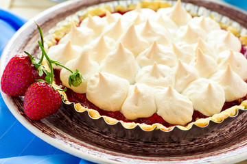 Strawberry tart with meringue on brown plate. Selective focus
