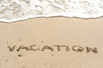 VACATION written on sand, tropical beach and wave background