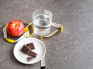 Roter Apfel, Schokolade, Massband und ein Glas Wasser