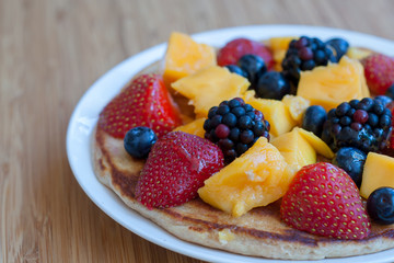 Pancake with fruit and berries in the plate on the wooden table