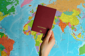 Fototapeta na wymiar red passport on the world map in women's hands