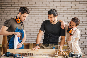 young carpenter with students in woodworking workshop show how working with planer