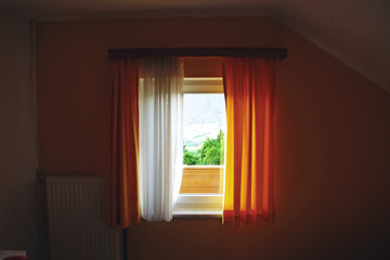 rustic window with curtains overlooking the green meadow in the village