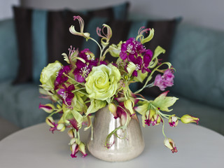 Bouquet of yellow roses with red flowers with buds in a vase on a white table