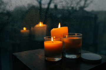 Three burning candles on table, cozy rainy day an home