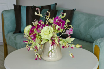 Bouquet of yellow roses with red flowers with buds in a vase on a white table
