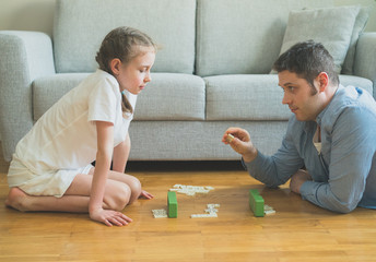 Father and daughter playing dominoes at home.