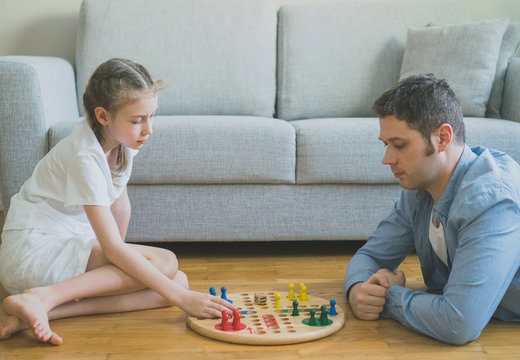 Little girl and her father playing ludo.