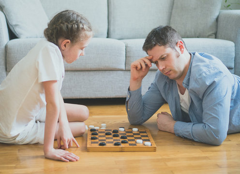 Father and daughter playing checkers board game.