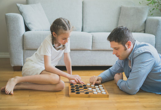 Father and daughter playing checkers board game.