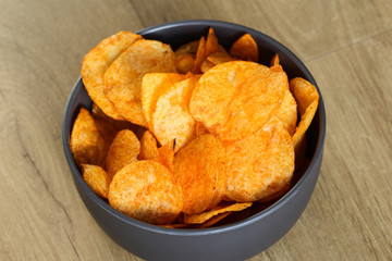 Spiced paprika Potato chips in a bowl on a wooden background