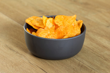 Spiced paprika Potato chips in a bowl on a wooden background