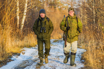 Naklejka premium Two hunters in the forest in late autumn