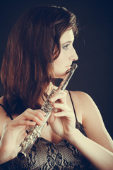 Woman playing transverse flute on black.