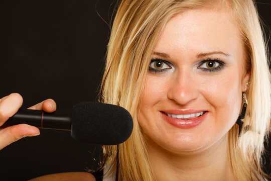 Blonde woman singing to microphone