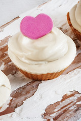 One decorated capkake with cashew cream on a white aged board