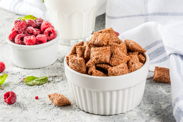 Healthy breakfast ingredients. Breakfast cereal, milk or yogurt glass, raspberries and mint on grey stone background, copy space