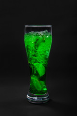 Summer green drink with lemon, lime and mint, ice on isolated black background. Direct perspective, cool, refreshing