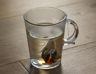 Glass of blueberry fruit tea with tea bag on wooden background