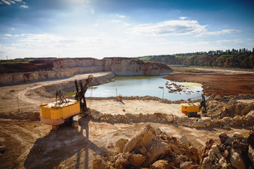 Fototapeta na wymiar Opencast sand mining quarry with excavator and other machinery at work, industrial production of pit, gravel, minerals and ore
