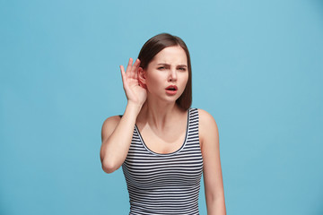 The young woman is listening something on the blue background.