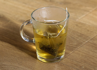 glass of Raspberry tea with tea bag on wooden background