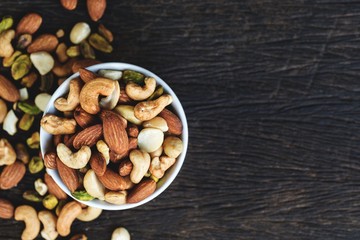 Healthy food and snack : mixed nuts in white ceramic bowl from above,  Walnut, pistachios, almonds, hazelnuts and cashews...