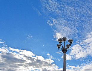 Old style street lamp on the quay promenade, cloudy blue sky on background