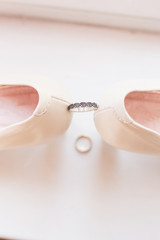 Wedding silver ring with black patterns between the bride's shoes on a white background. Ring