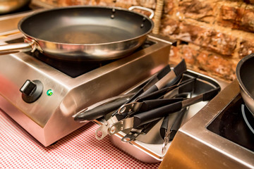 Small cooktop with frying pan and thongs