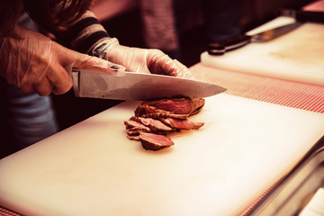 Hands slice piece of steak on white board