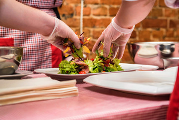 Hands in gloves mix salad with meat