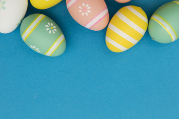 Easter holiday background. Pastel colored decorated easter eggs on a bright blue background