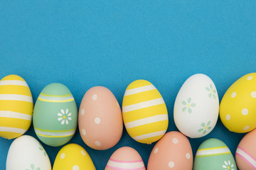 Easter holiday background. Pastel colored decorated easter eggs on a bright blue background
