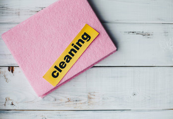 Cleaning house or office concept. Colorful pink dishwasher cloth brush and Cleaning inscription on...