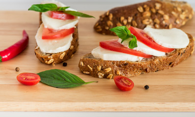 Sliced mozzarella with cherry tomato, basil and cereal bread