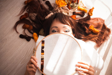 Young beautiful woman is engaged in embroidering a dagger on the embroidery frame in a colored...