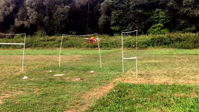 Hexacopter in training flying through obstacles at low altitude over the lawn.

