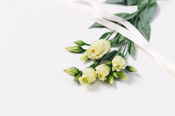 Bunch of white Eustoma on light white background with copy space. Floral greeting card for invitation or congratulations.