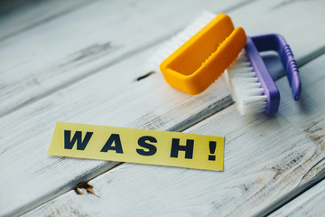 Cleaning house or office concept. Blue and yellow cleaning brushes and WASH inscription on a white...
