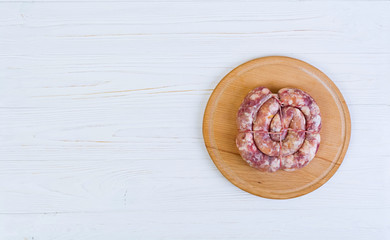 Fresh raw sausage on wooden background