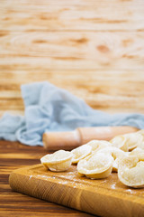 Homemade raw dumplings, pelmeni, on wooden background.