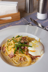 Pasta Carbonara. Spaghetti with bacon, parsel and parmesan cheese. Pasta Carbonara on white plate with parmesan on dark background. Italian food concept.