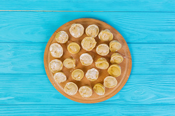 Homemade raw dumplings, pelmeni, on wooden background.