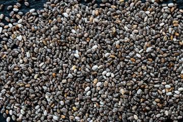 Chia seeds on black slate background, top view, macro