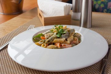 color Penne pasta in a creamy sauce on a white plate